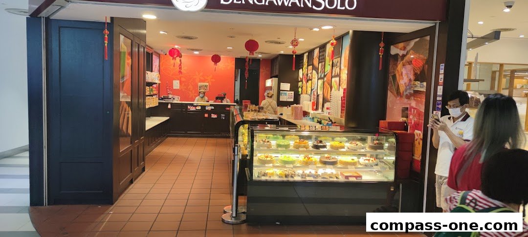 The entrance of Bengawan Solo bakery, showcasing a display of cakes and pastries, with staff behind the counter.