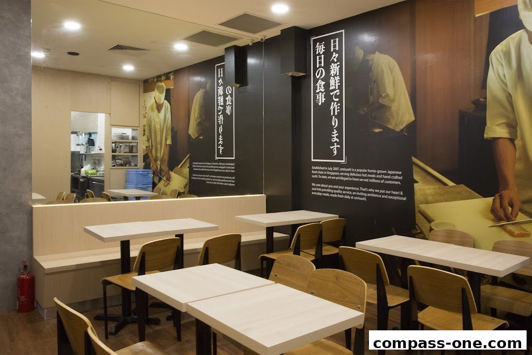 Interior of a sushi restaurant with tables, chairs, and wall art depicting chefs.