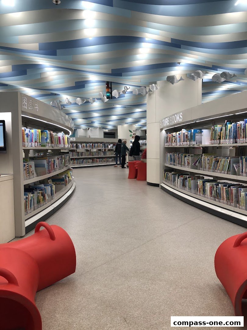 Interior of a modern library with bookshelves, reading areas, and decorative whale figures on the ceiling.