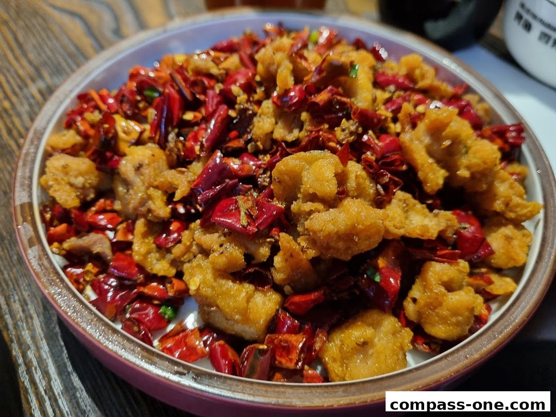 A close-up of a bowl filled with crispy fried chicken and dried chili peppers.
