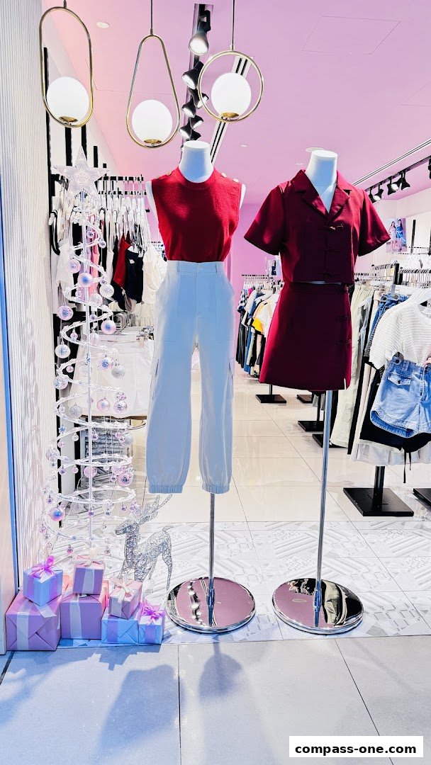 A stylish shop window display featuring mannequins in fashionable outfits and festive decorations.