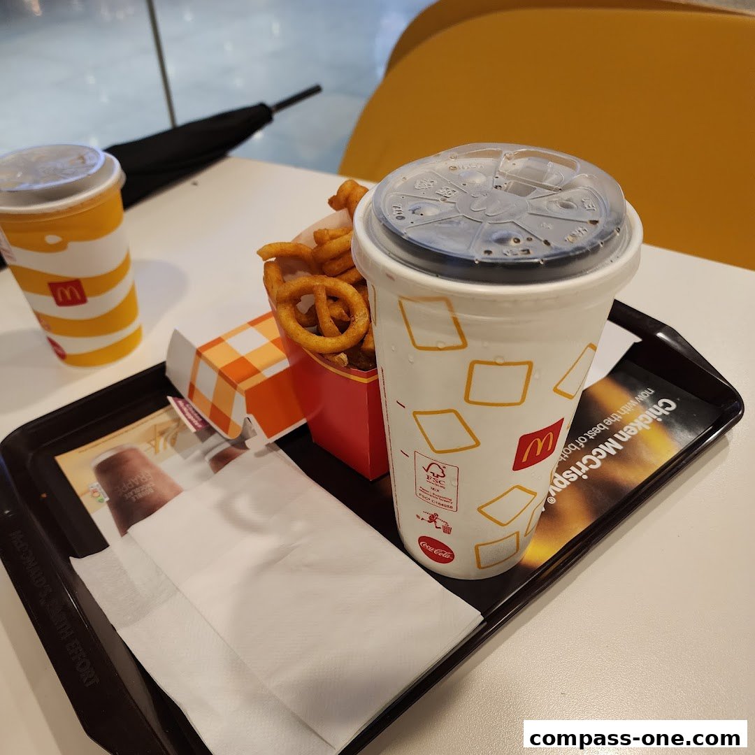 A tray of McDonald's food including curly fries, a large drink, and a smaller drink.
