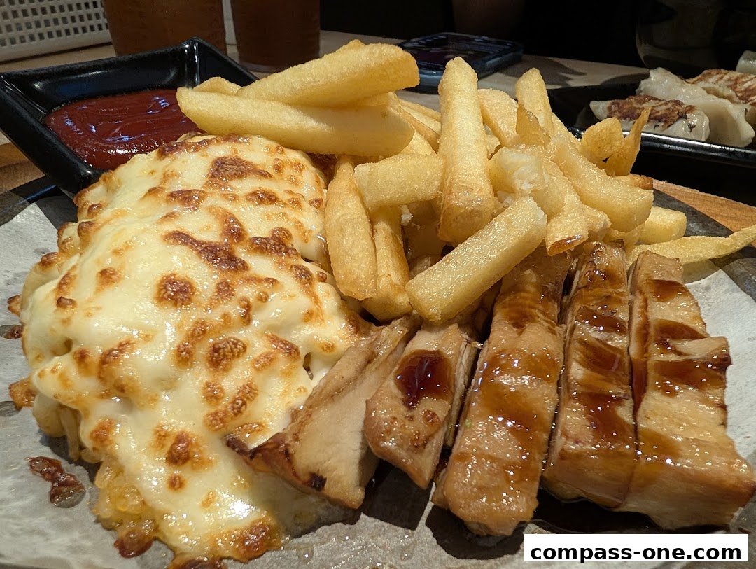 A plate of food featuring cheesy baked dish, french fries, and sliced meat with sauce.
