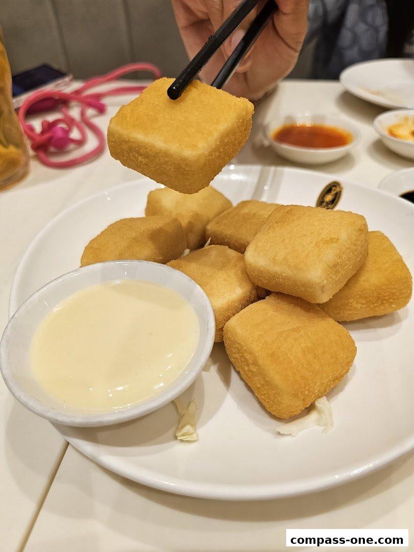A plate of golden fried tofu cubes with a side of creamy dipping sauce.