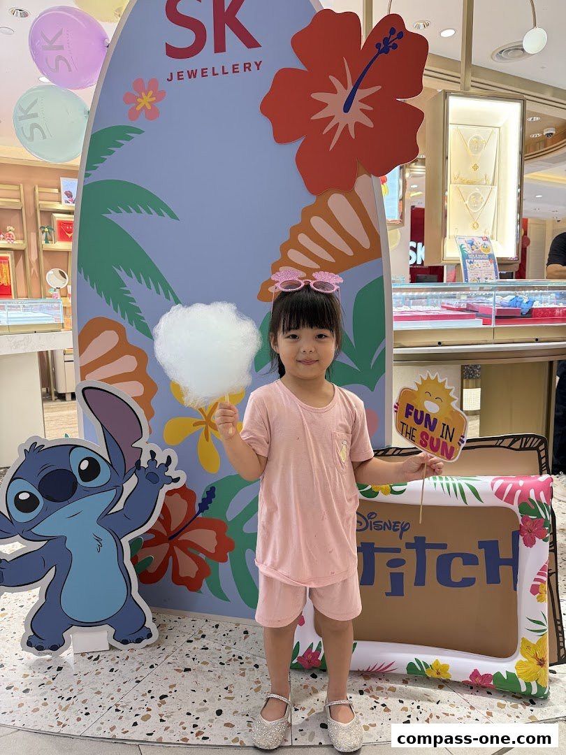 A young girl poses with cotton candy in front of a SK Jewellery display featuring Stitch.