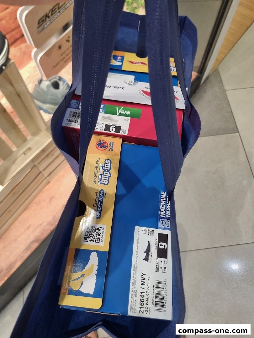 A blue tote bag filled with Skechers shoe boxes, showcasing various styles and sizes.