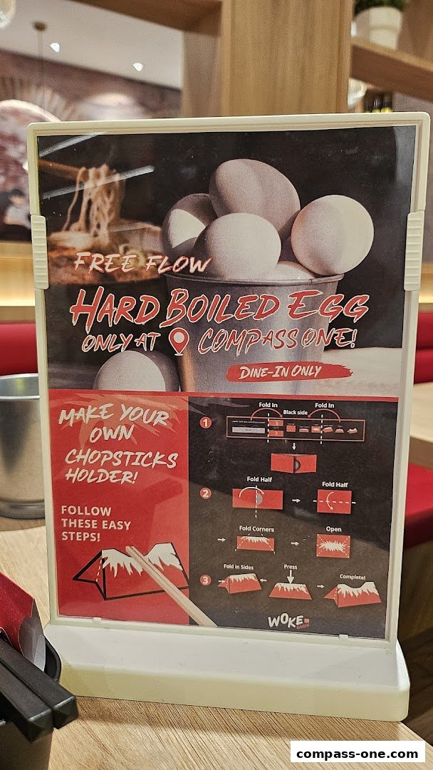 A sign advertising free flow hard-boiled eggs and instructions for making a chopsticks holder at WOKE Ramen.