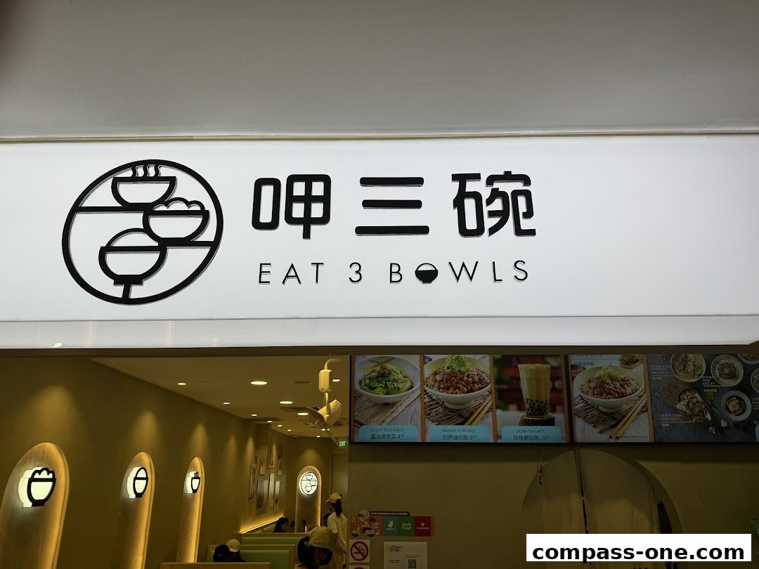 The exterior of Eat 3 Bowls restaurant with its logo and menu displays.