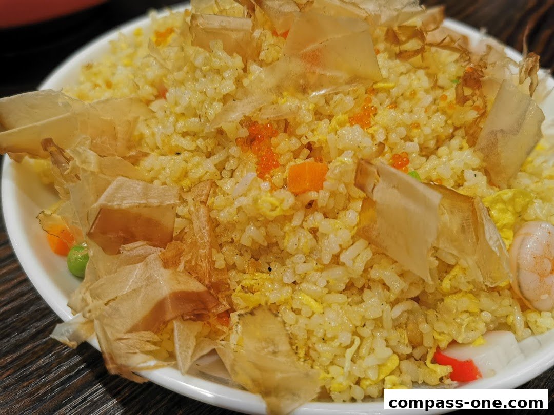 A close-up of a delicious fried rice dish topped with bonito flakes and garnished with shrimp and roe.
