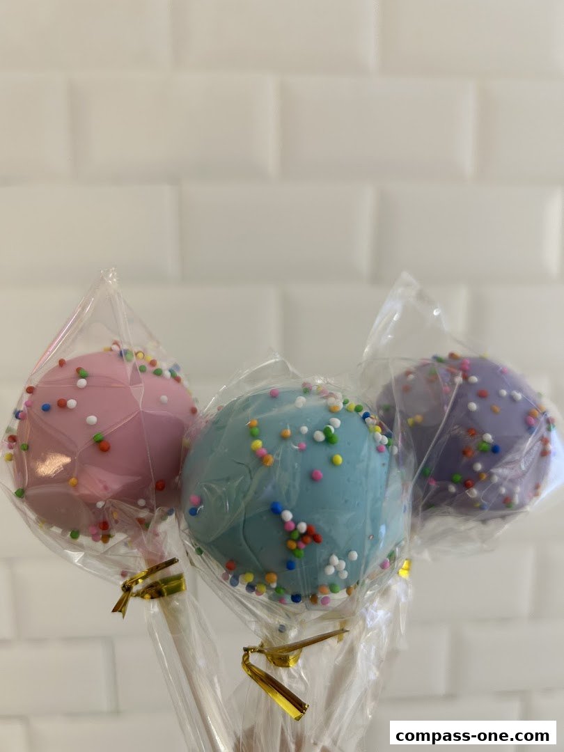 Three colorful cake pops with sprinkles, individually wrapped in plastic.