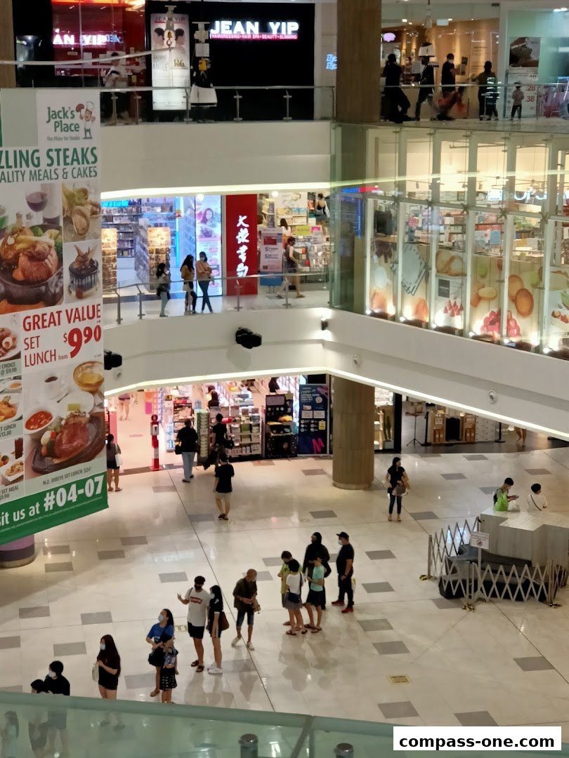 A busy shopping mall interior with various shops and people walking around.