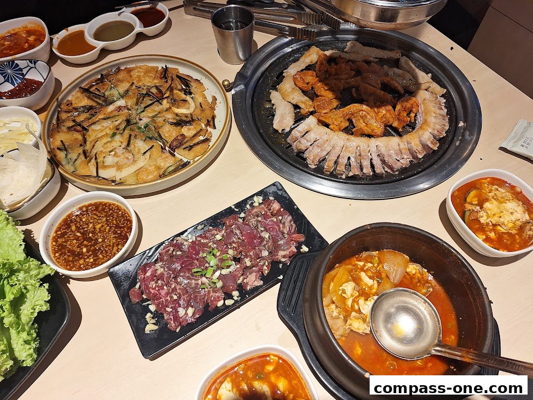 A table laden with various Korean dishes, including grilled meats, a savory pancake, and stews.