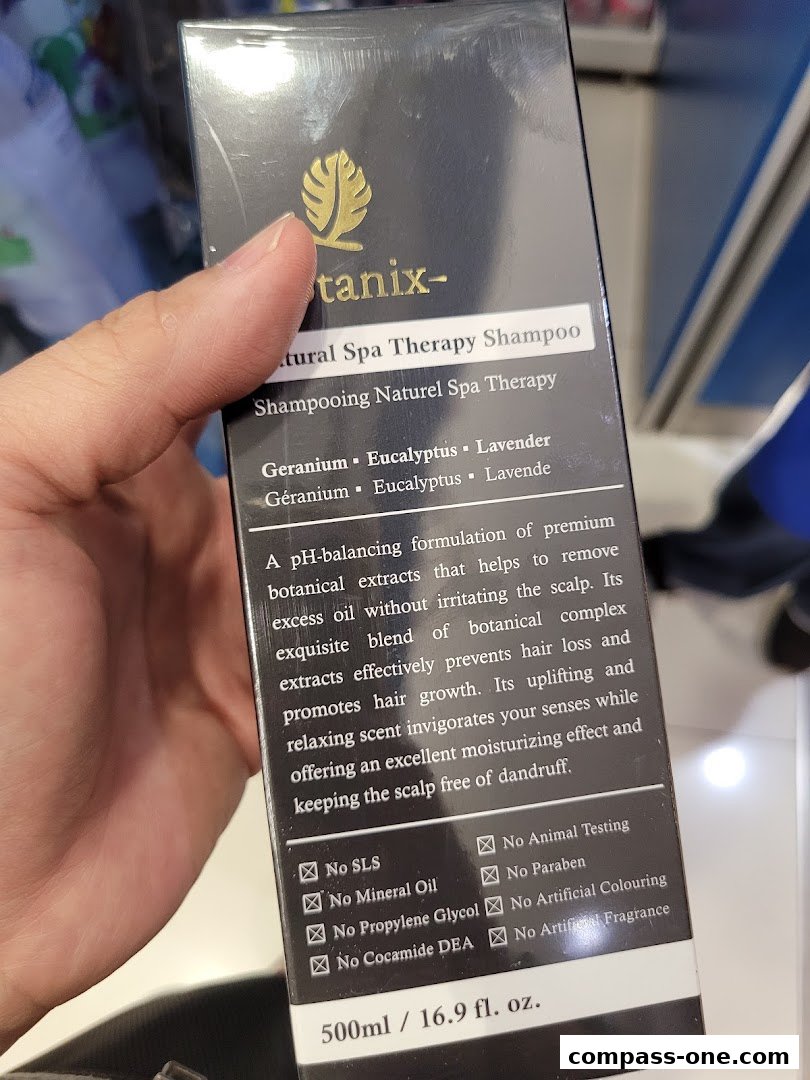 A hand holds a bottle of Tanix Natural Spa Therapy Shampoo.