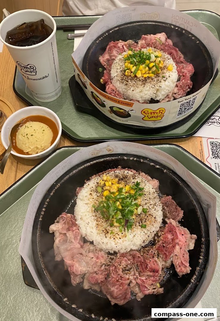 Two sizzling hot plates of Pepper Lunch with rice, beef, corn, and a side of mashed potatoes and drink.