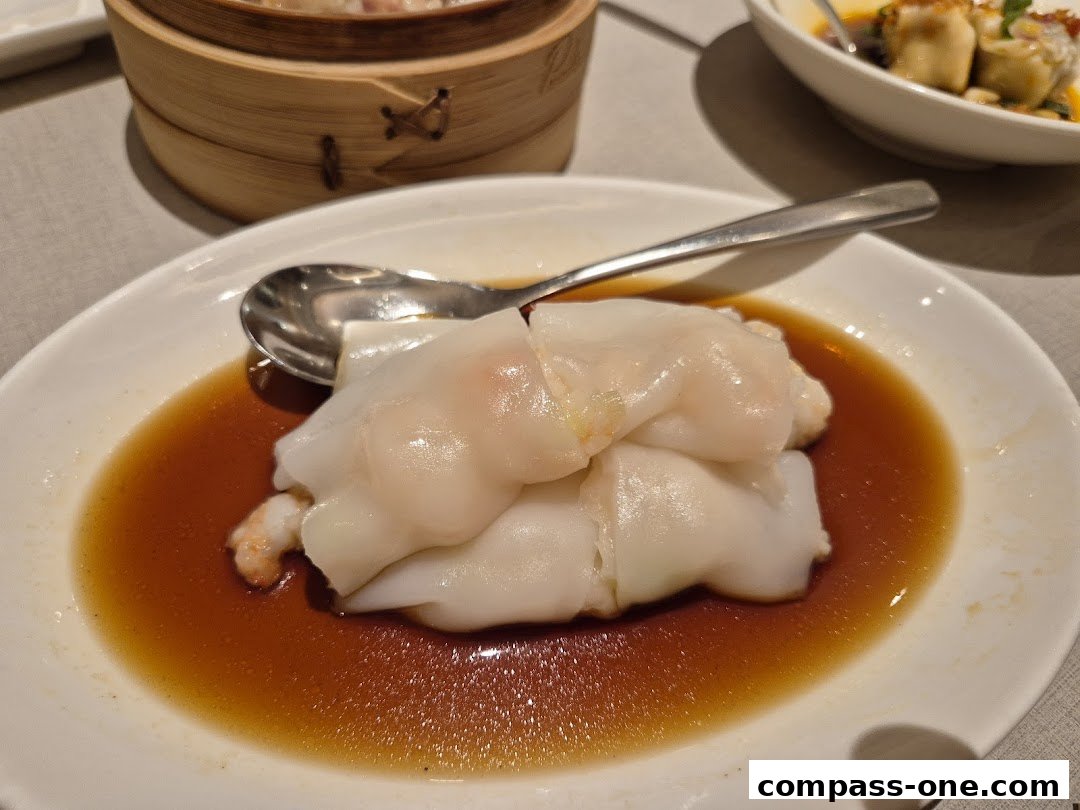 A close-up of a delicious shrimp rice noodle roll served with soy sauce and a spoon.