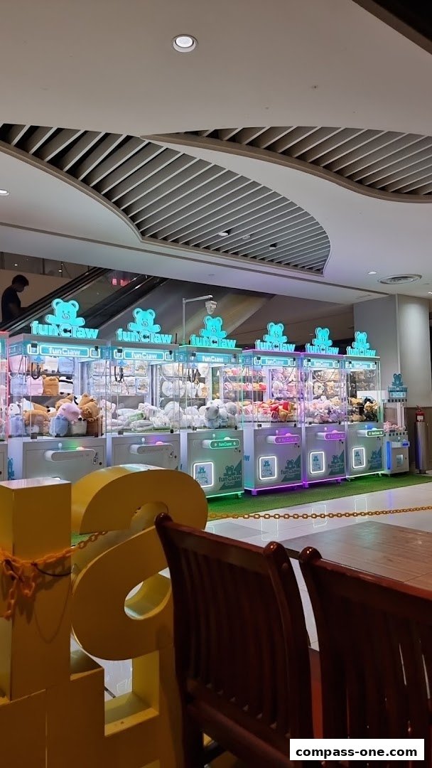 A row of brightly lit claw machines filled with plush toys in a shopping mall.
