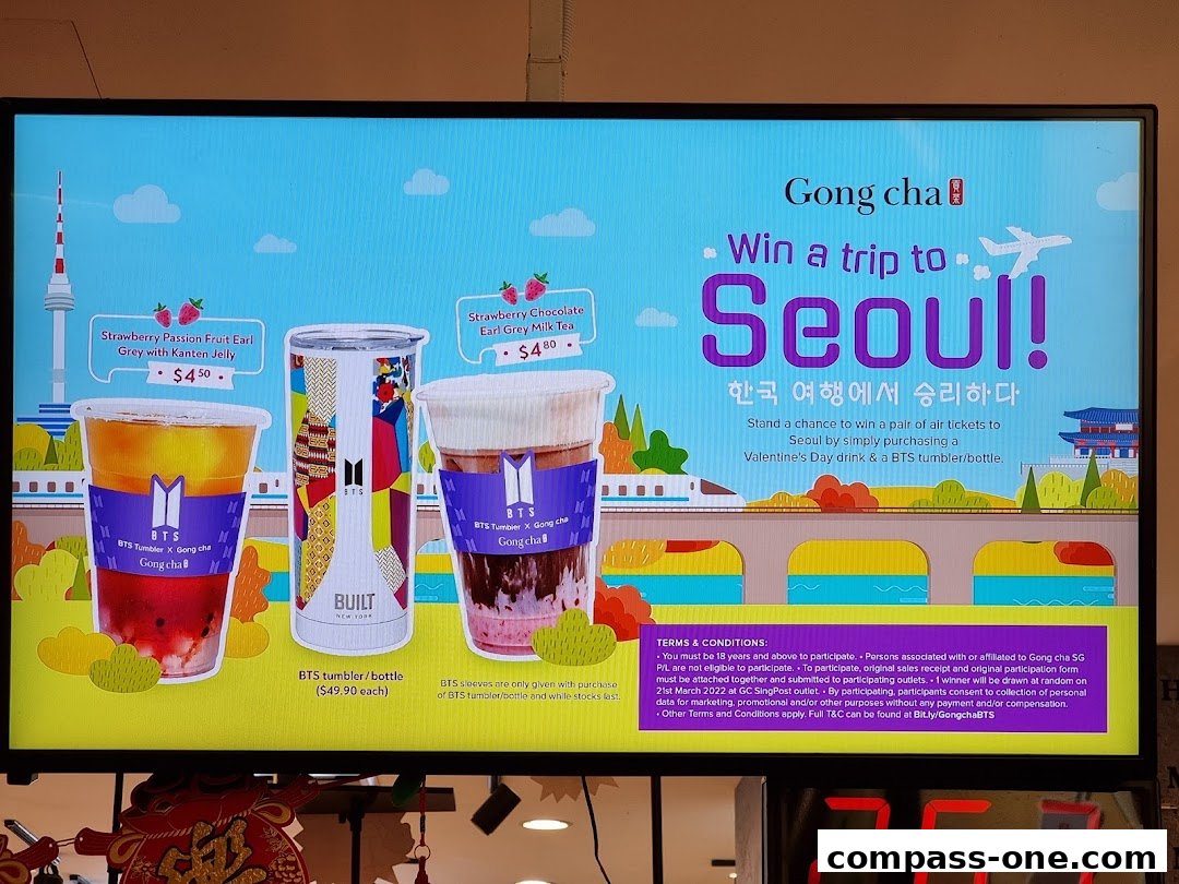 A promotional display for Gong Cha featuring drinks, a BTS tumbler, and a chance to win a trip to Seoul.