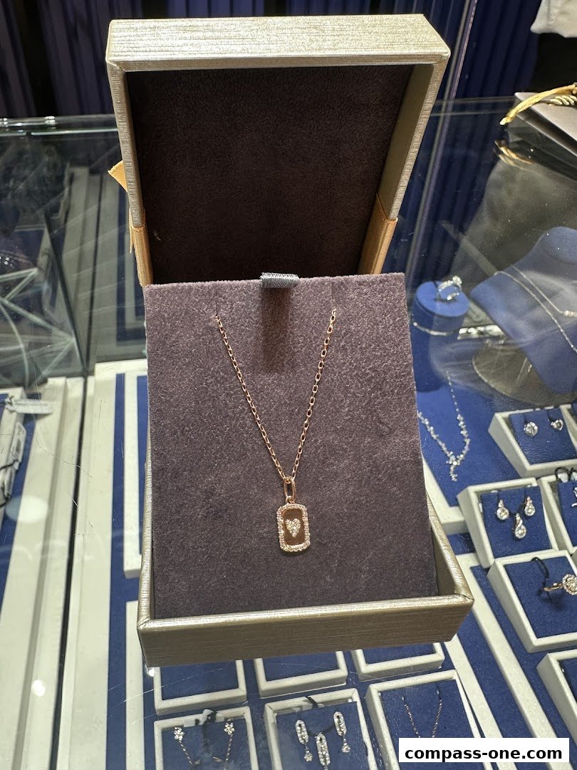 A rose gold necklace with a diamond-encrusted heart pendant in a jewelry box.