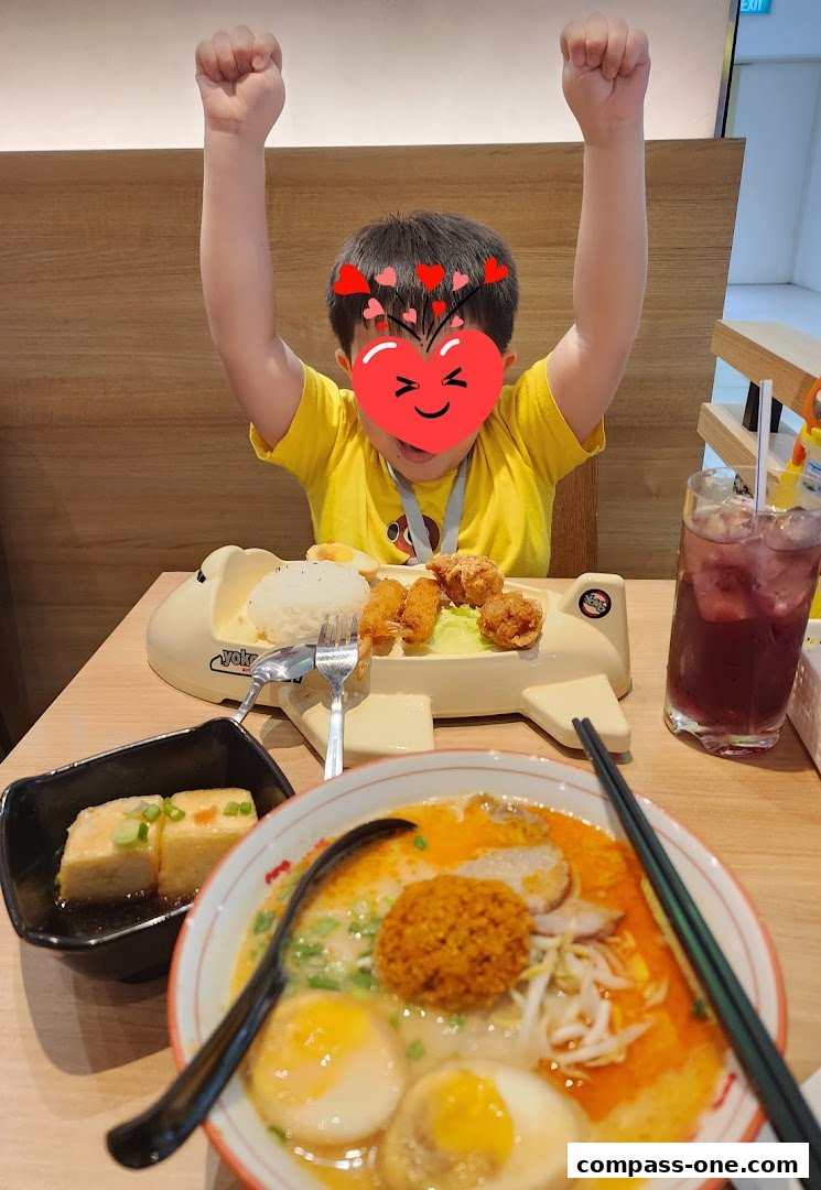 A child with a heart sticker on their face enjoys a meal at Ajisen Ramen.