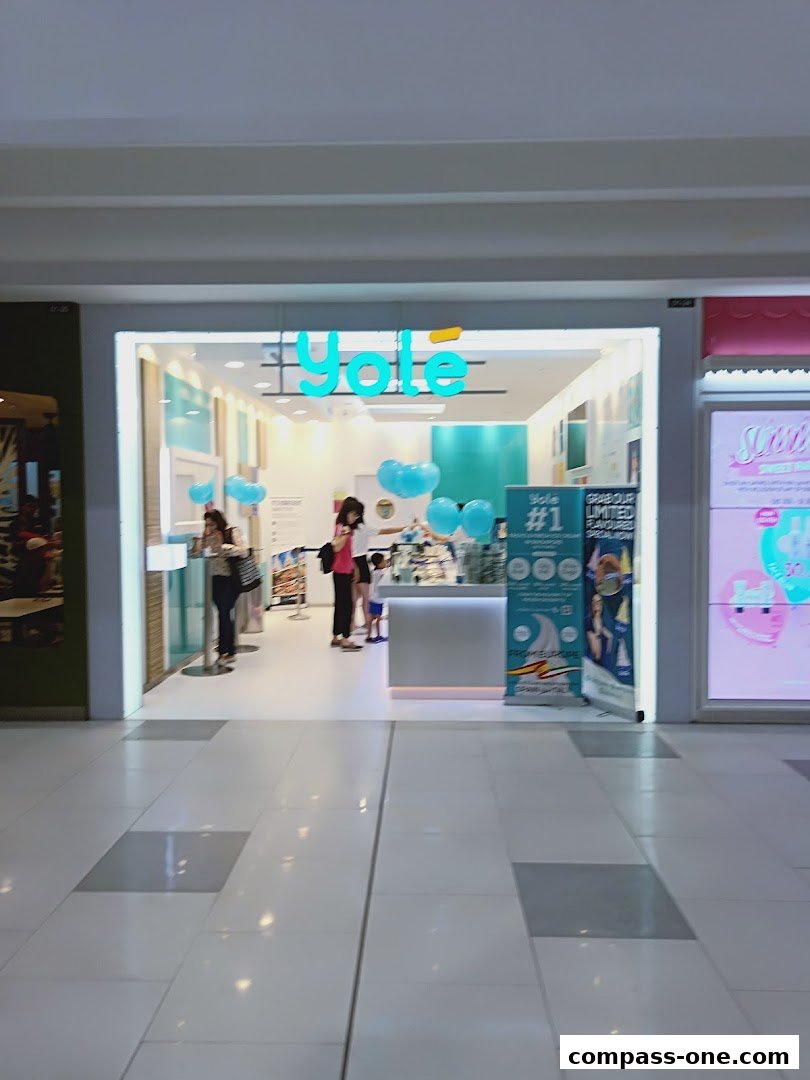 The entrance of a Yole frozen yogurt shop with people inside and blue balloons.