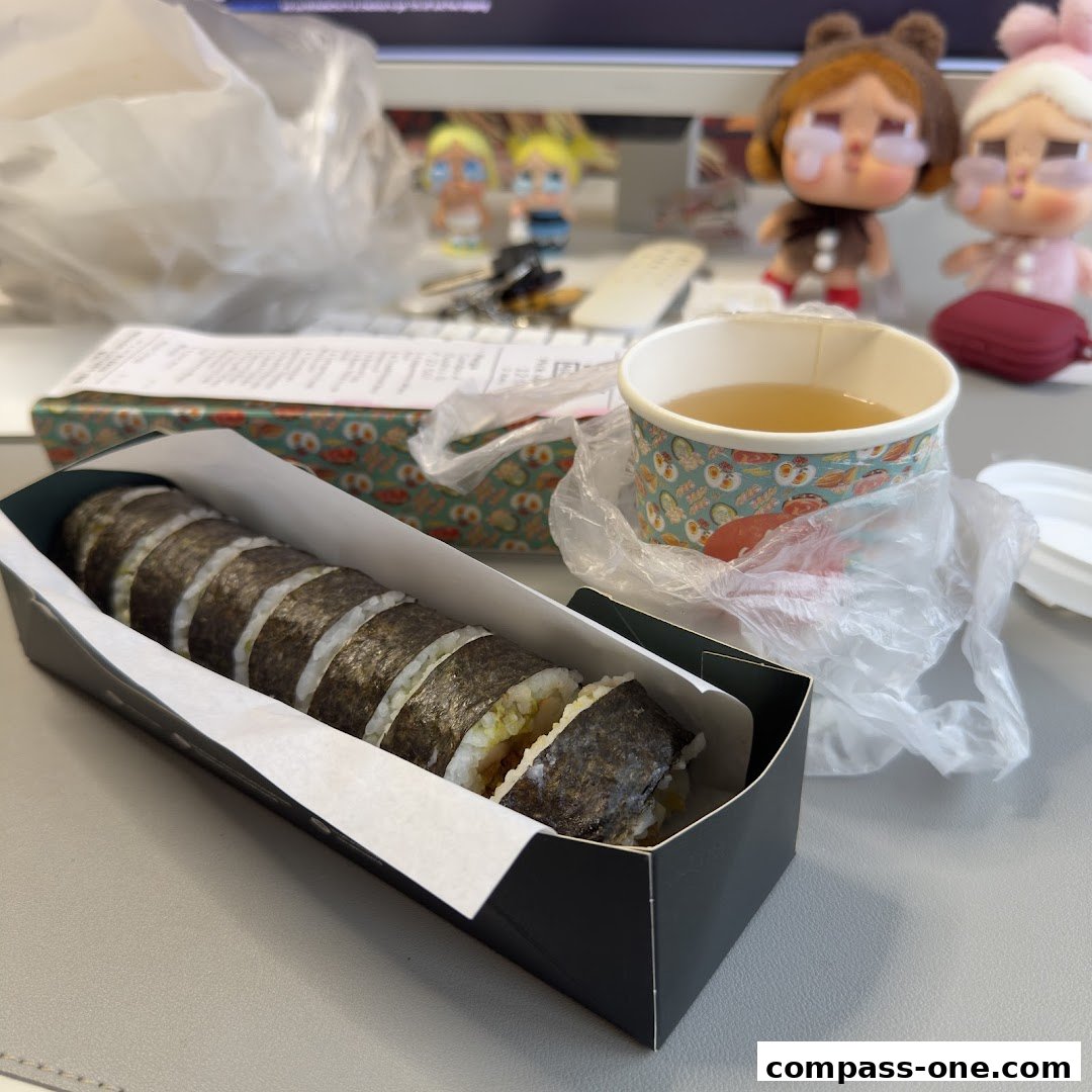 A box of sushi rolls and a cup of tea on a desk with decorative figures.