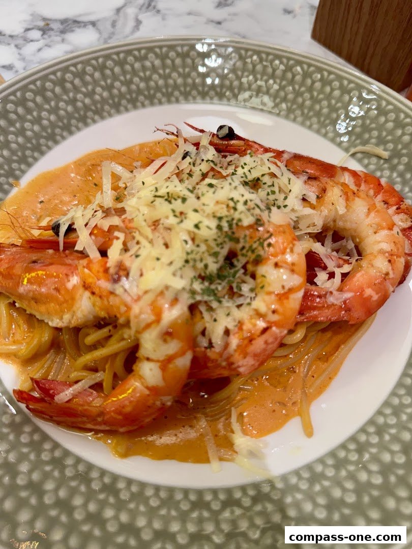 A close-up of a pasta dish with large prawns, creamy sauce, and grated cheese.