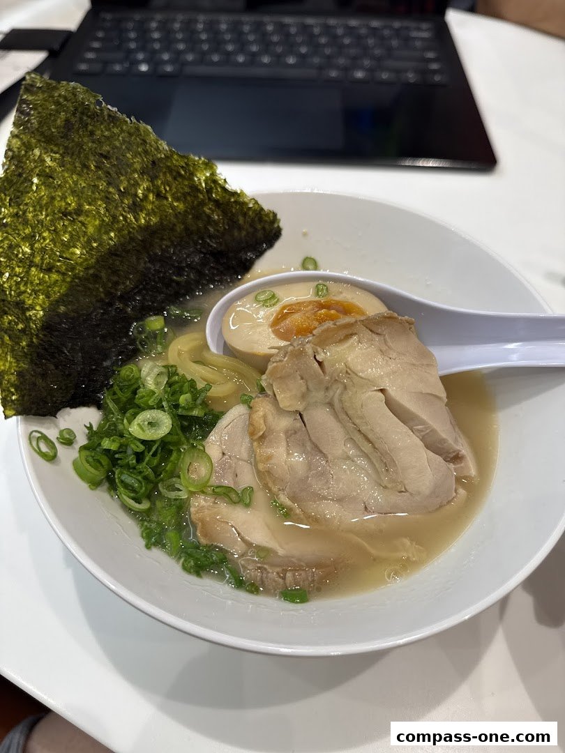 A bowl of delicious ramen with tender pork, a soft-boiled egg, and nori seaweed.