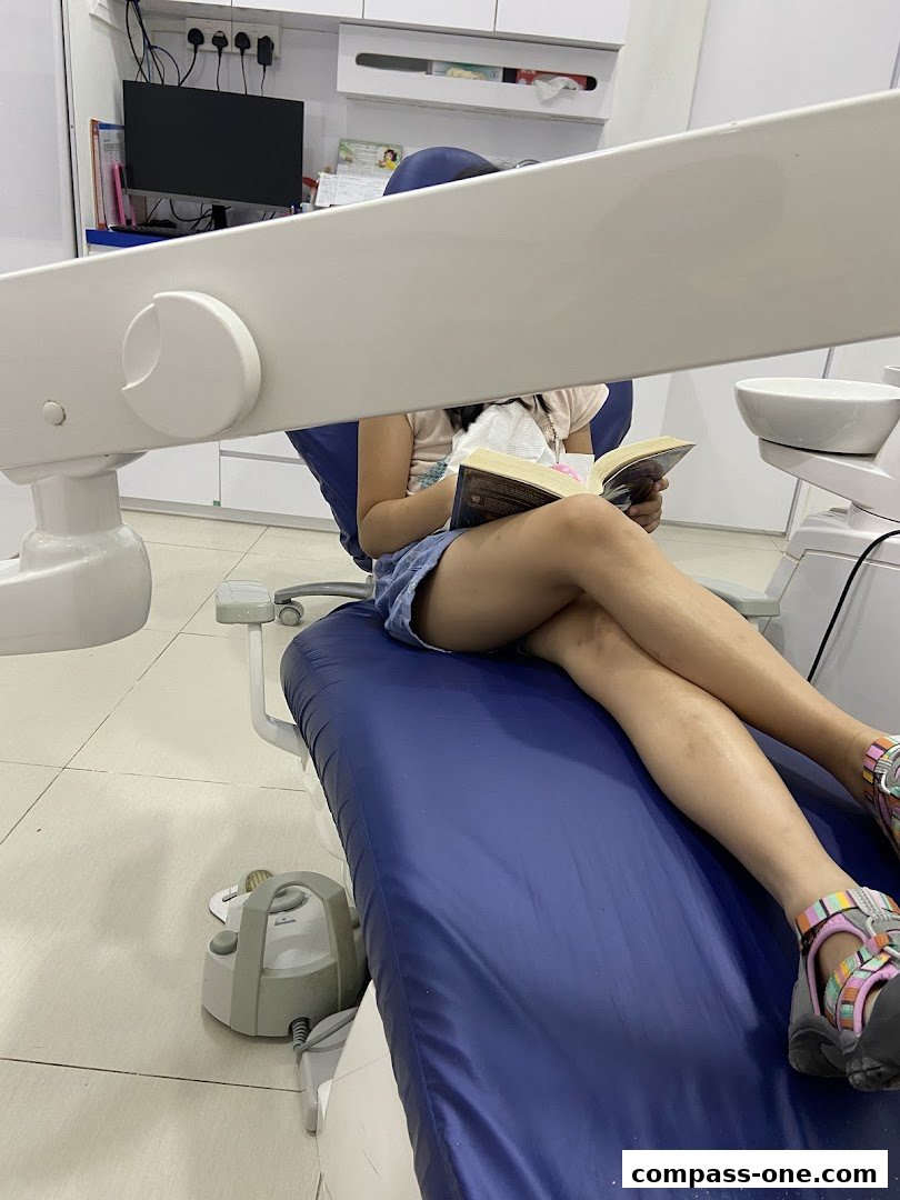 A person sits in a dental chair reading a book while waiting for their appointment.