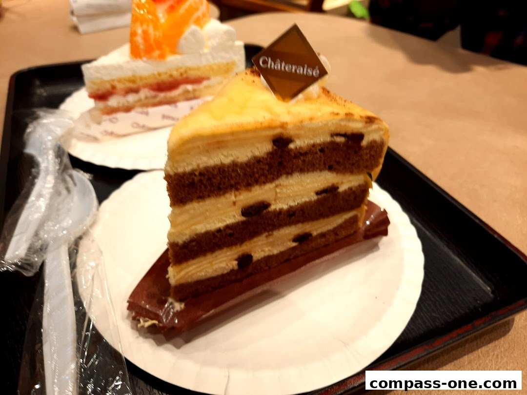A slice of layered chocolate and cream cake with a Châteraisé logo on a black tray.