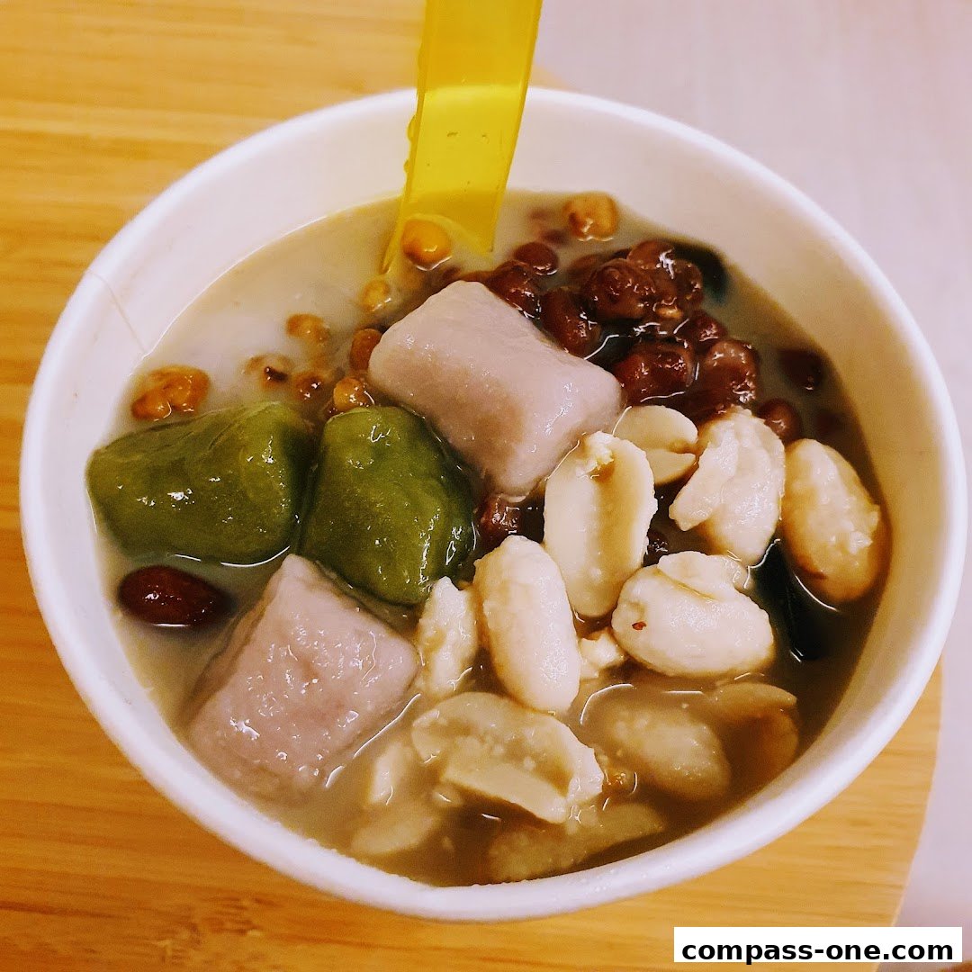 A close-up shot of a delicious Taiwanese dessert with taro balls, peanuts, red beans, and green mochi.