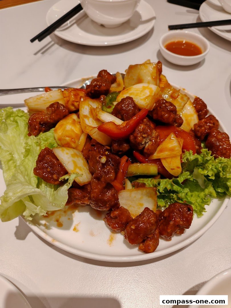 A plate of sweet and sour pork with pineapple and vegetables, served with lettuce.