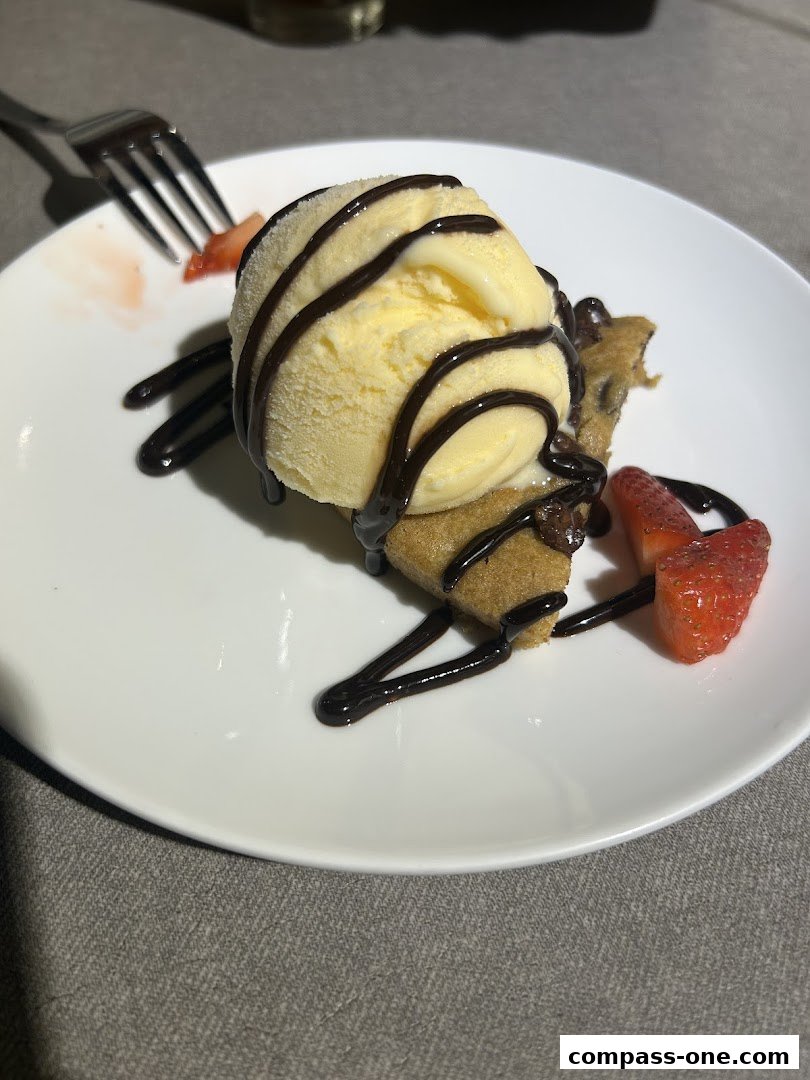 A delicious dessert featuring a cookie, ice cream, chocolate syrup, and strawberries.