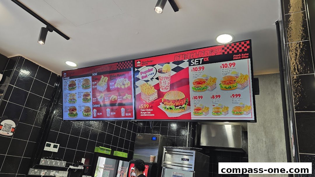 A digital menu board displaying various burgers, sides, drinks, and set meals at Shiok Burger.