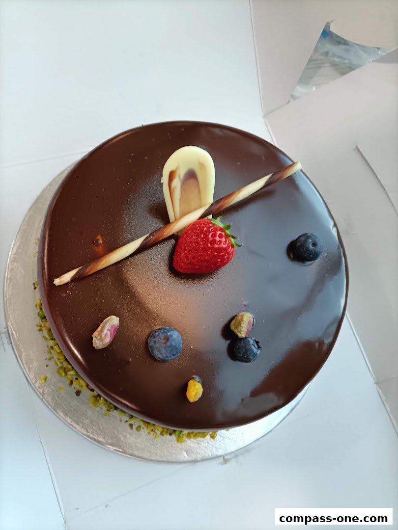 A decadent chocolate cake topped with fresh berries, pistachios, and chocolate garnishes.