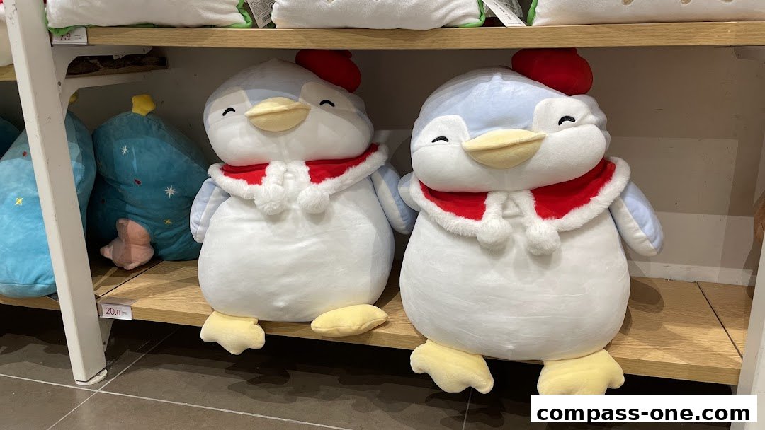 Two large plush toys resembling penguins wearing festive red and white scarves.