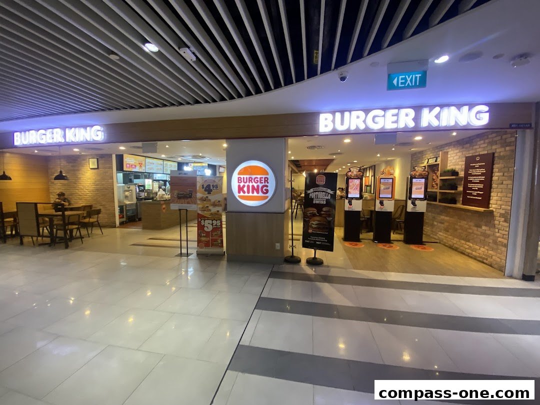 Burger King restaurant entrance with digital ordering kiosks and seating area.