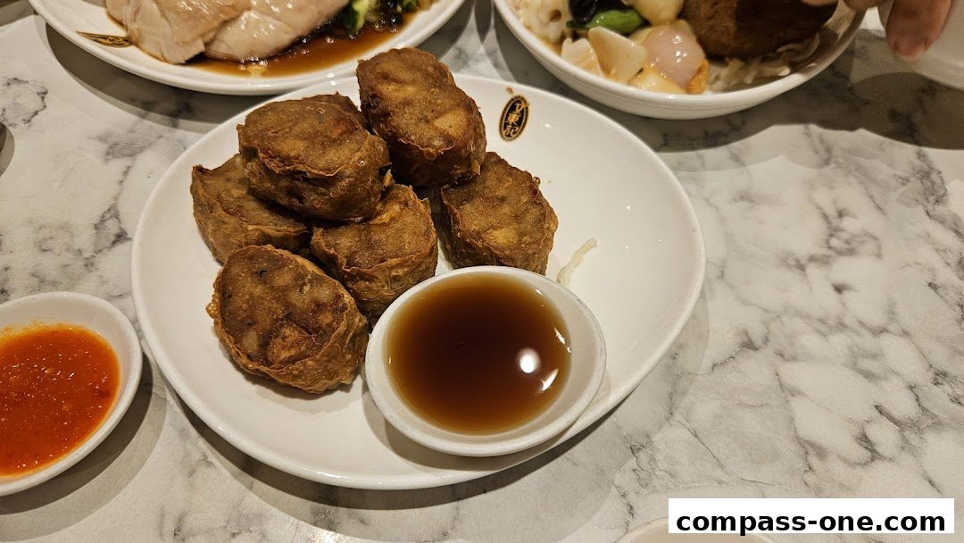 A plate of crispy fried rolls with a dipping sauce and a side of chili sauce.