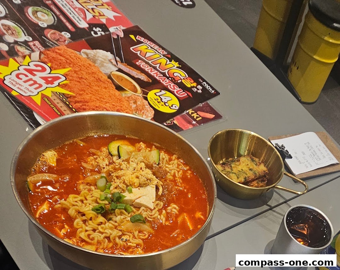 A table at POCHA! Korean Street Dining with a steaming bowl of ramen and a side dish.