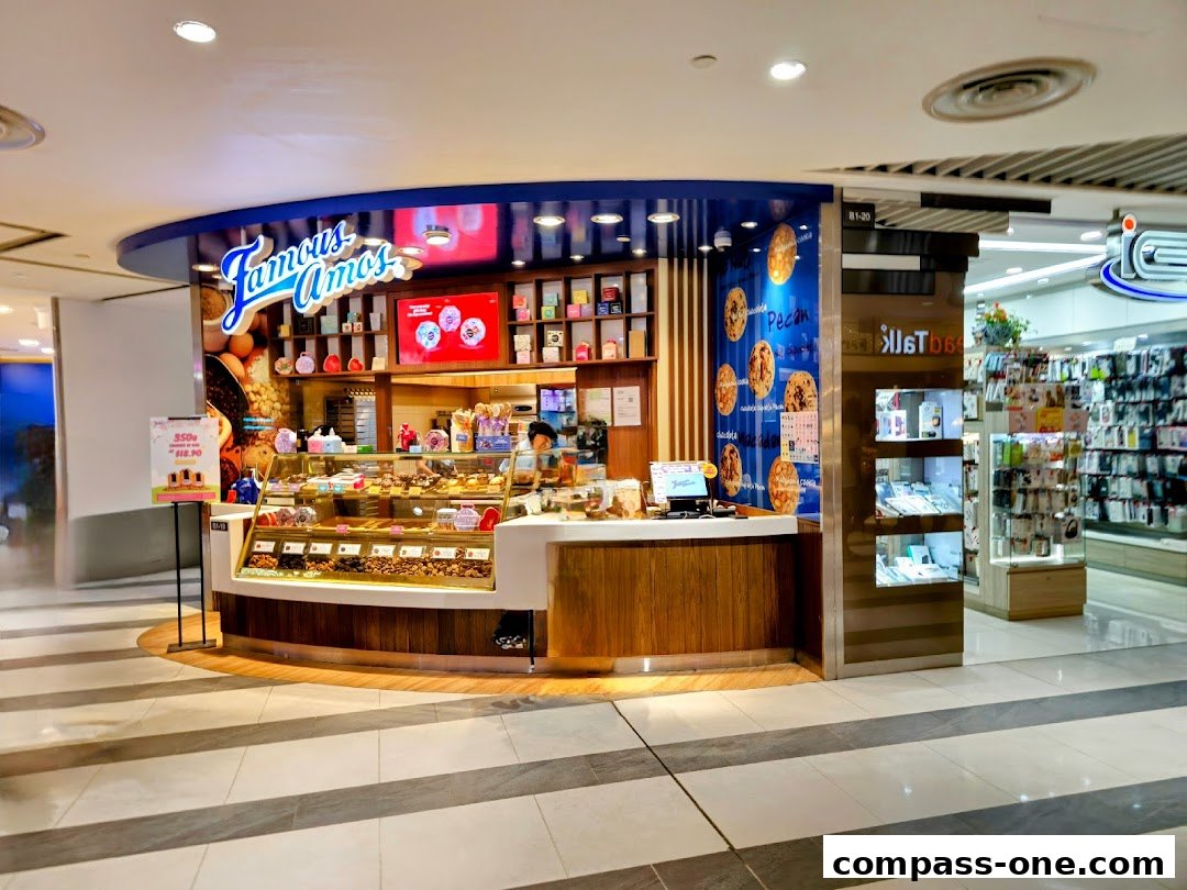 A Famous Amos cookie shop with a display of cookies and a cashier.