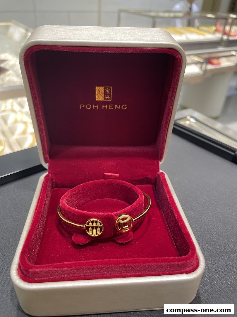 A gold bracelet with abacus and coin charms in a Poh Heng Jewellery box.