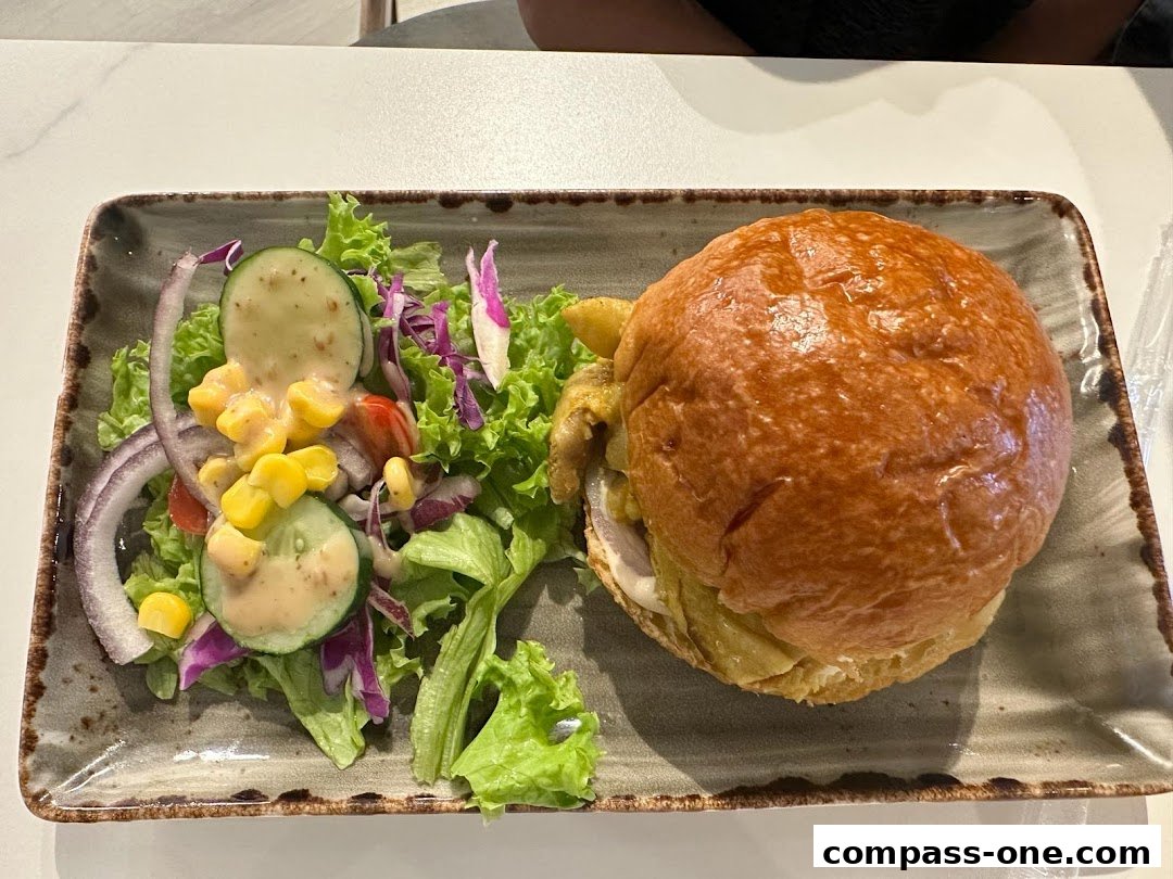 A close-up shot of a gourmet burger and a fresh side salad on a rectangular plate.