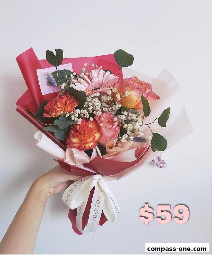 A hand holding a beautiful bouquet of pink and orange flowers with a white ribbon.