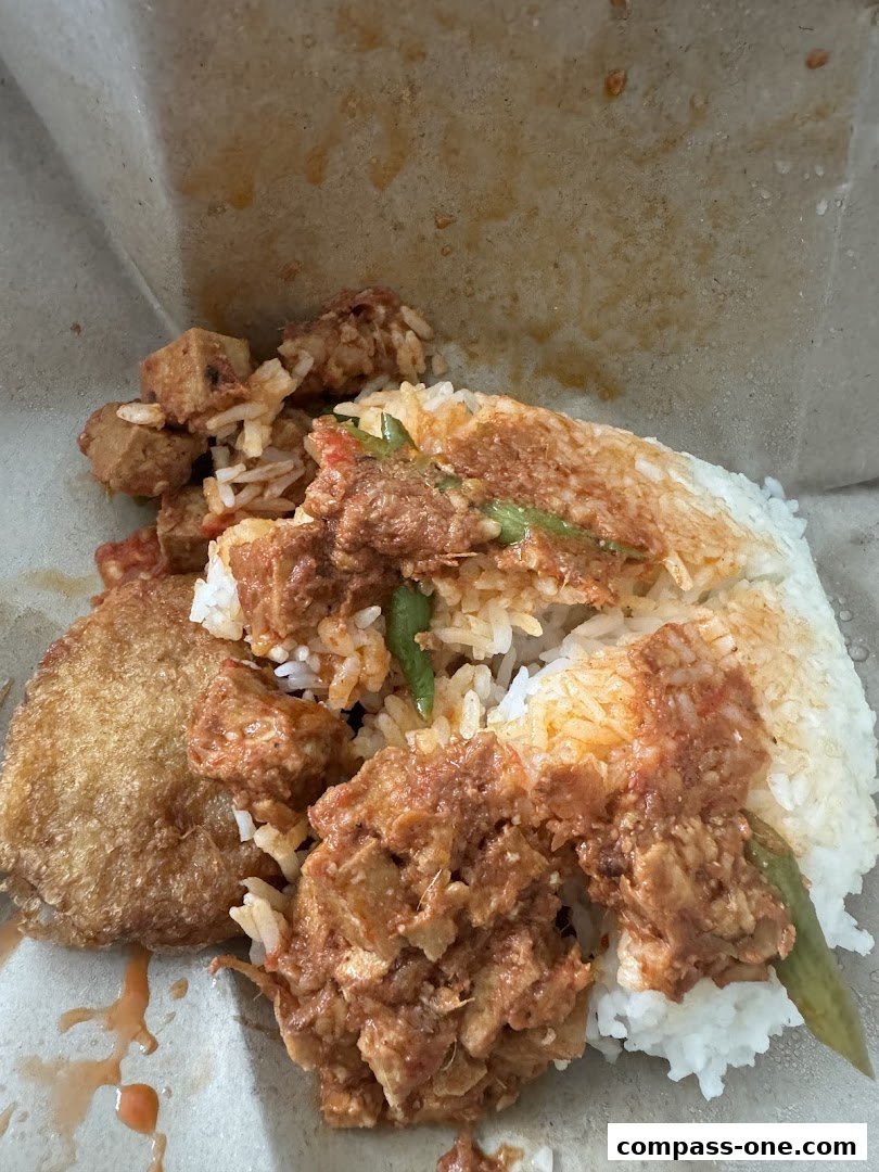 A close-up of a delicious rice dish with various toppings and a fried item.