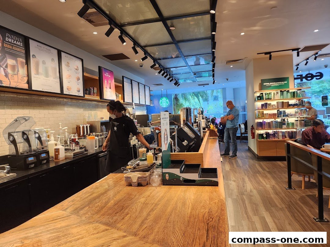 Interior view of a Starbucks coffee shop with staff preparing drinks and customers seated.