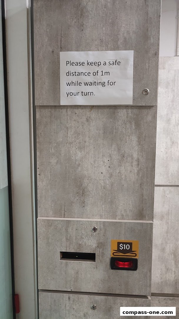 A concrete wall with a sign about social distancing and a payment slot with a $10 label.