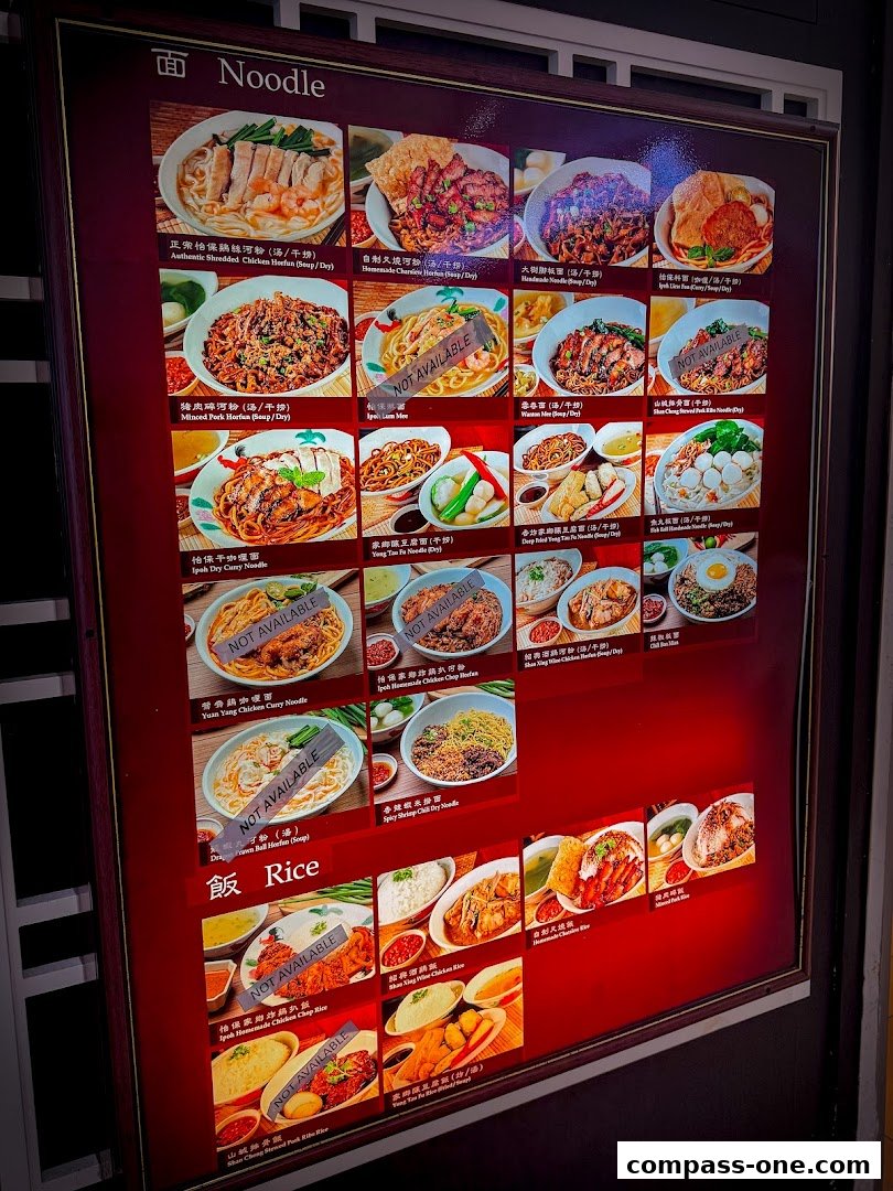 A brightly lit menu board showcasing various noodle and rice dishes from Shan Cheng Ipoh Delicacies.