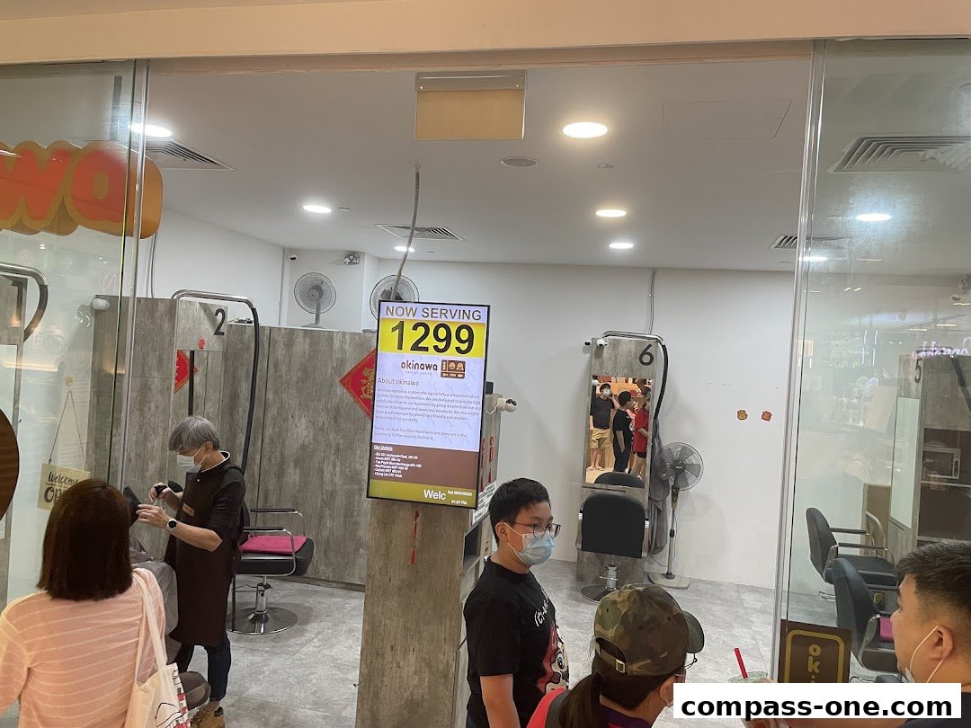 Interior of Okinawa Hair Salon with staff and customers, featuring a digital display.