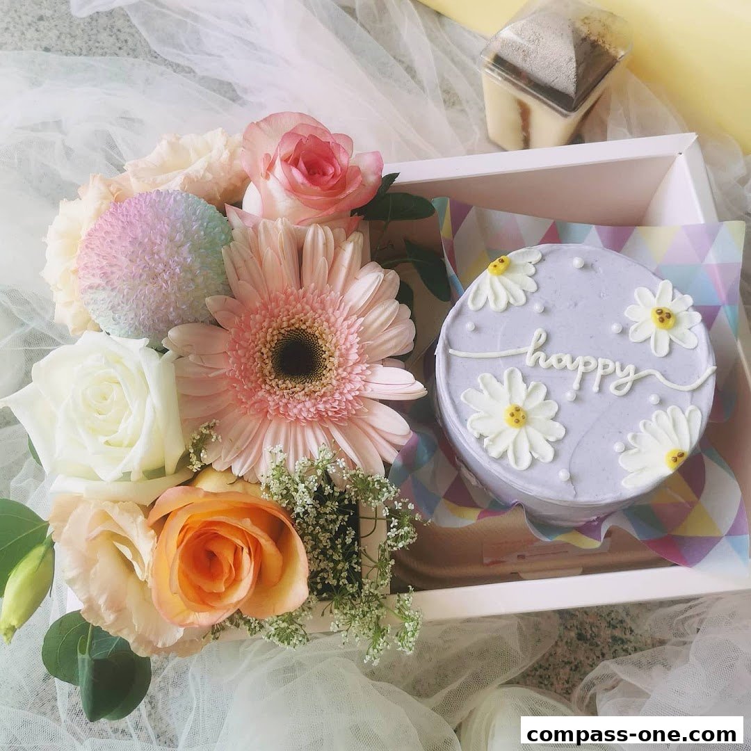 A pastel-colored cake decorated with daisies and the word 'happy', alongside a bouquet of fresh flowers.