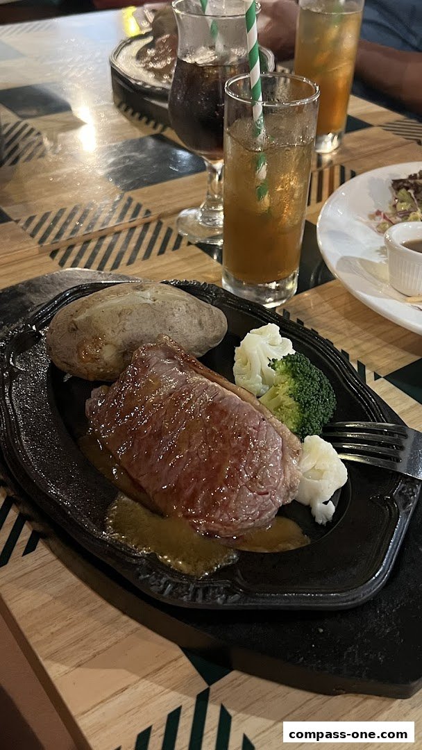 A juicy steak with a baked potato and vegetables served on a sizzling platter with drinks.