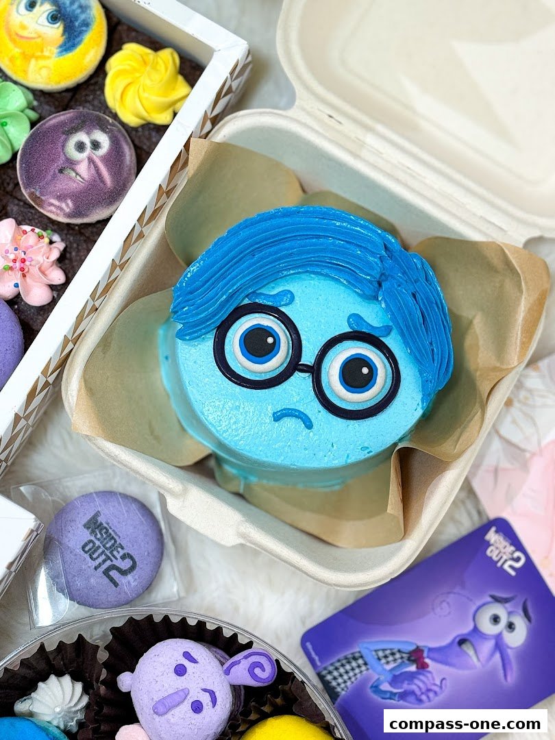 A close-up of a Sadness-themed cake and macarons, with Inside Out 2 branding.